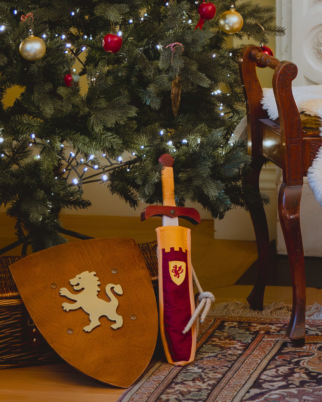 Decorative sword and shield in front of a Christmas tree with ornaments.