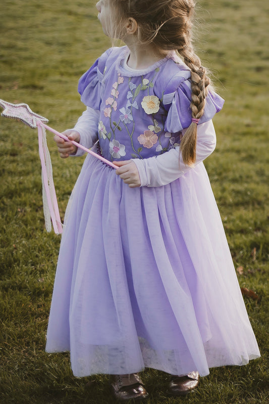 A girl holding a wand in our new purple repunzel fancy dress