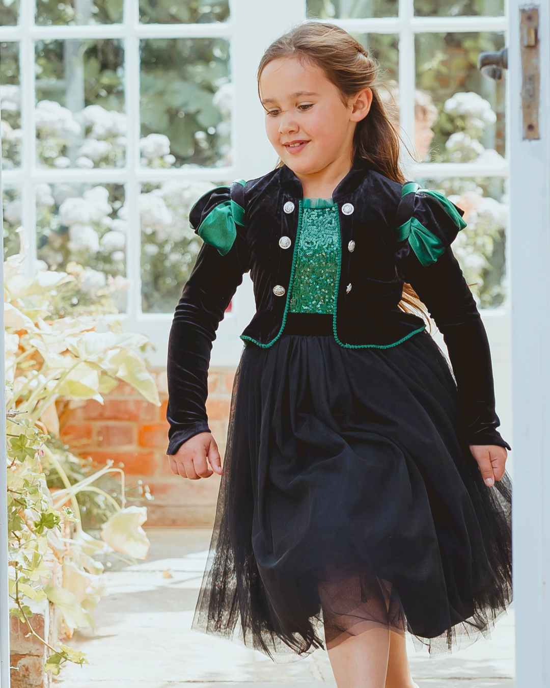 Girl wearing a green and black velvet witch costume dress with a tulle skirt
